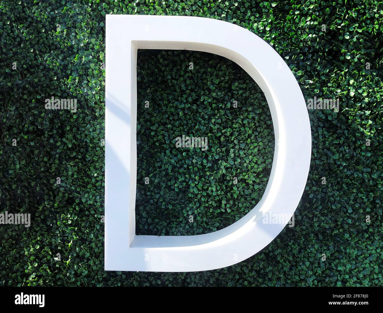 grande lettera bianca fotografata su erba verde all'aperto Foto Stock