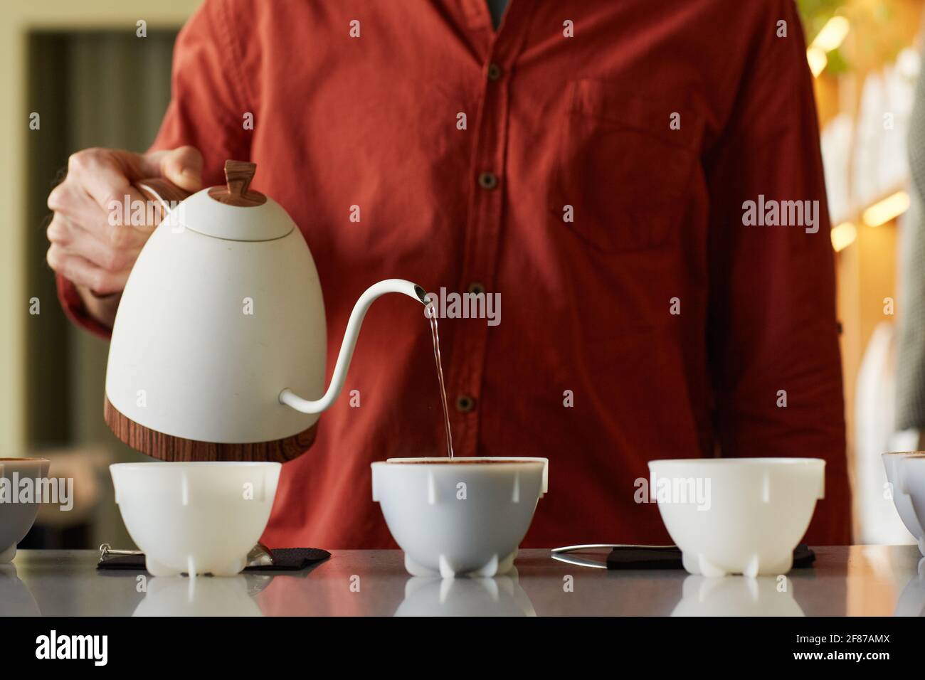 Ritratto troncato della barista femminile che versa il caffè nelle tazze in fila sul supporto bar, spazio per la copia Foto Stock