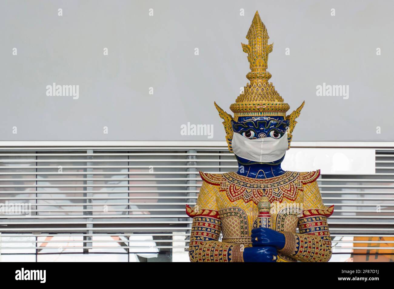 la tradizionale statua gigante tailandese all'aeroporto di Suvarnabhumi indossa una faccia protettiva maschera per incoraggiare l'uso della maschera e l'osservazione di sociale distanza t Foto Stock