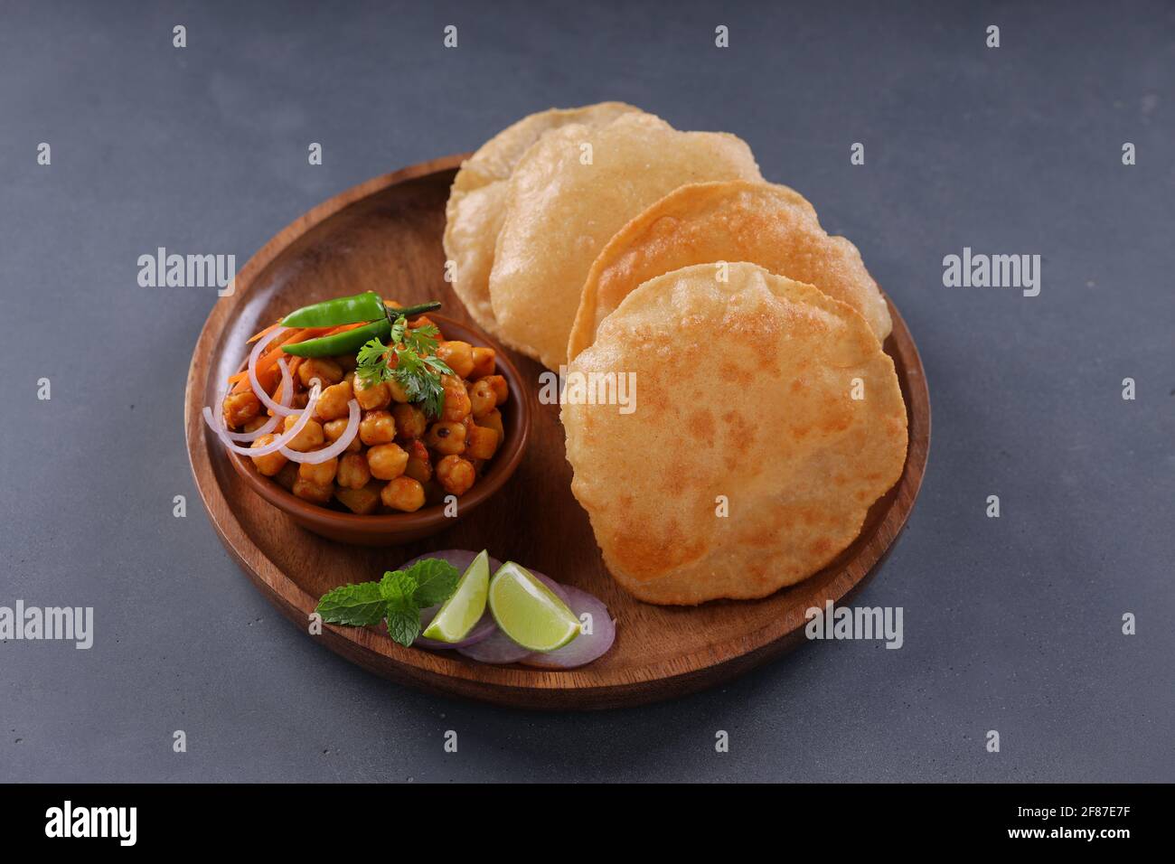 Colazione indiana _Poori con ceci chana masala curry, gustoso piatto indiano fatto usando farina di grano di tutti gli scopi che è disposto in una piastra di legno con Foto Stock