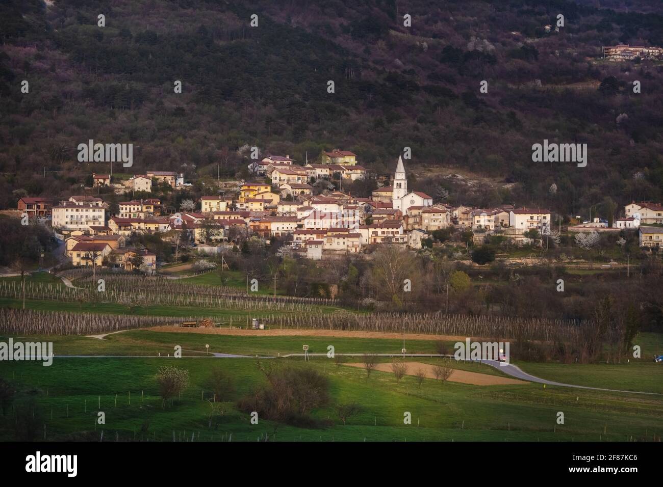 Tardo Afternon Tiro di Villaggio di Osek nella Valle di Vipava Slovenia. Situato nel mezzo della Valle. Surrogato da colline e zona coltivata. Molti Mon sacrale Foto Stock