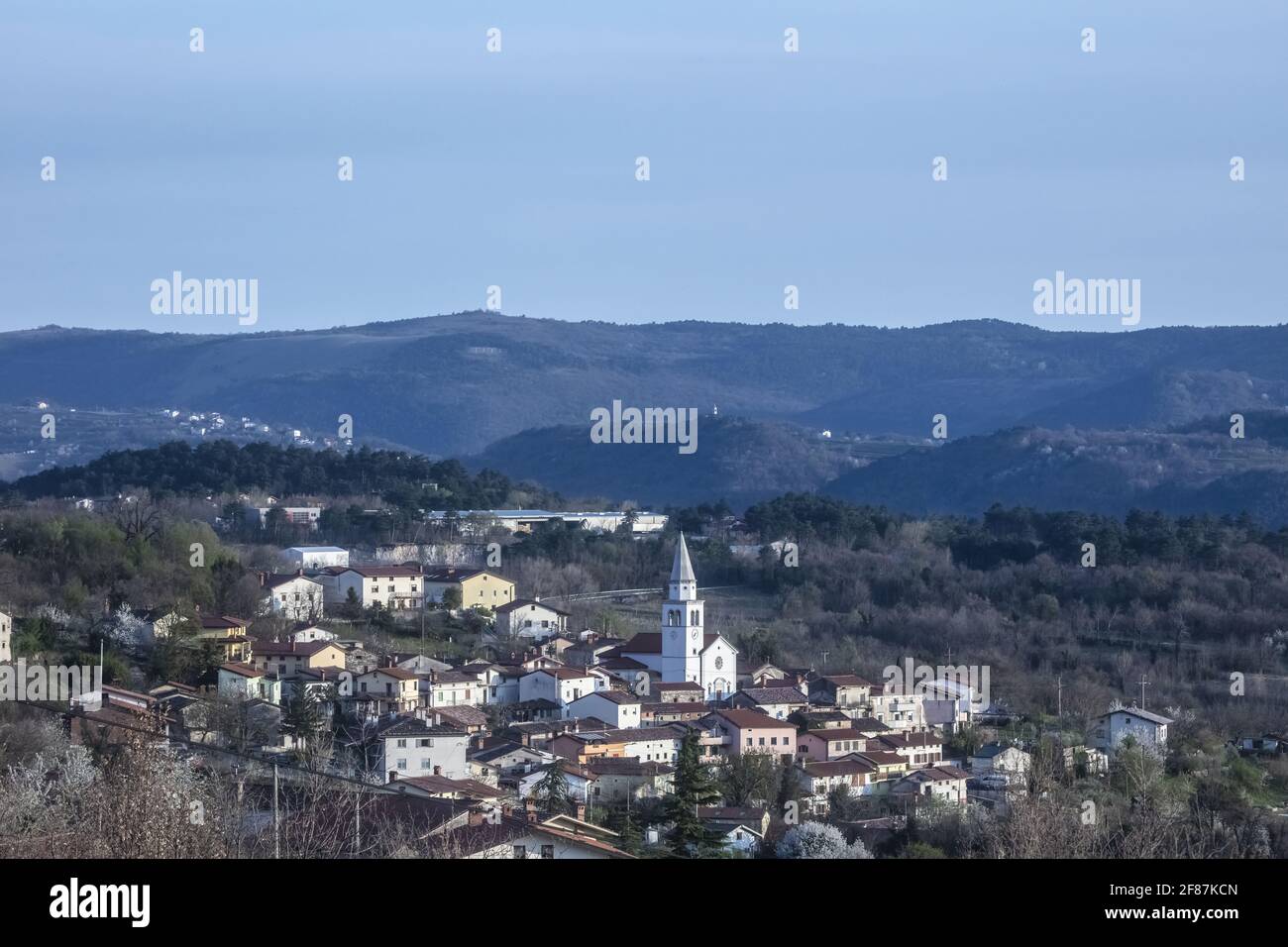 Tardo Afternon Tiro di Villaggio di Osek nella Valle di Vipava Slovenia. Situato nel mezzo della Valle. Surrogato da colline e zona coltivata. Molti Mon sacrale Foto Stock