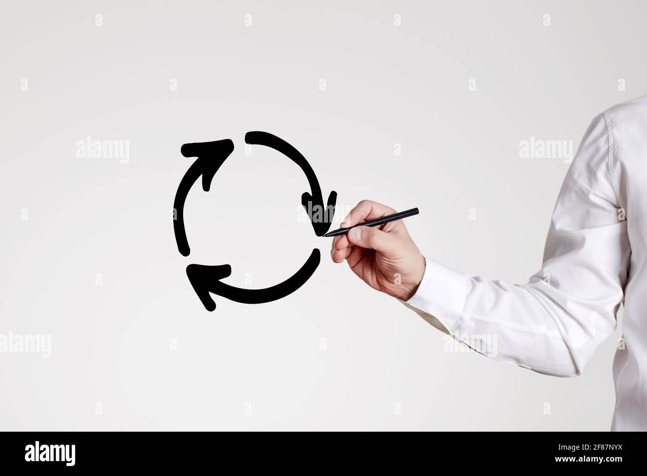 L'uomo d'affari disegna un cerchio di riciclaggio con frecce su sfondo grigio. Stagnazione economica o aziendale o concetto di riciclo. Foto Stock
