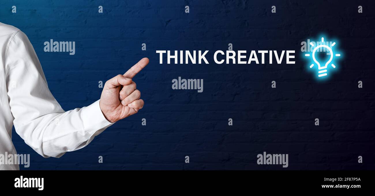 La mano dell'uomo d'affari punta alla parola pensa creativo con l'icona della lampadina della luce. Pensiero creativo nel concetto di business. Foto Stock