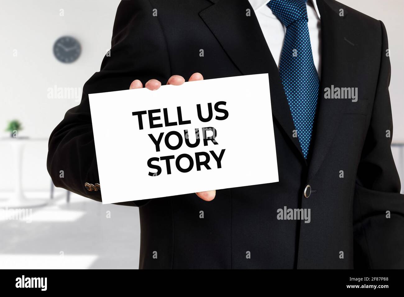 Uomo d'affari ha una carta con il messaggio raccontaci la tua storia. Concetto aziendale. Foto Stock