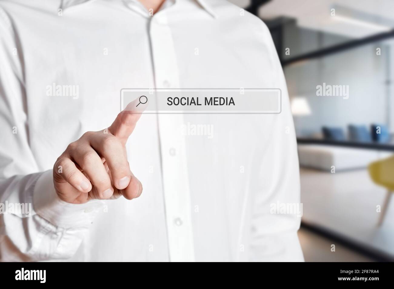 Mano dell'uomo d'affari premere l'icona della barra di ricerca su uno schermo virtuale con la parola social media. Foto Stock