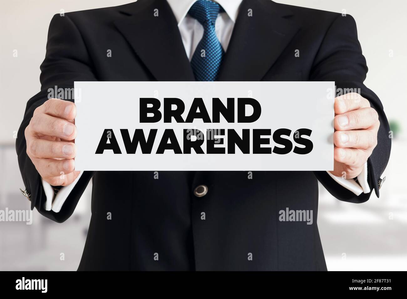 Uomo d'affari mostra un banner con il messaggio brand awareness. Concetto di branding della strategia di marketing aziendale. Foto Stock