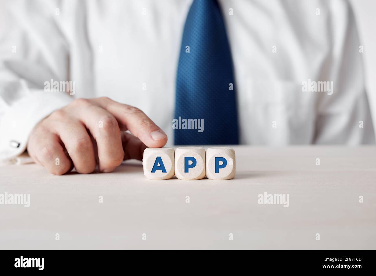 Uomo d'affari premendo il dito sui cubetti di legno con la parola app. Sviluppo di applicazioni e tecnologia di comunicazione. Foto Stock