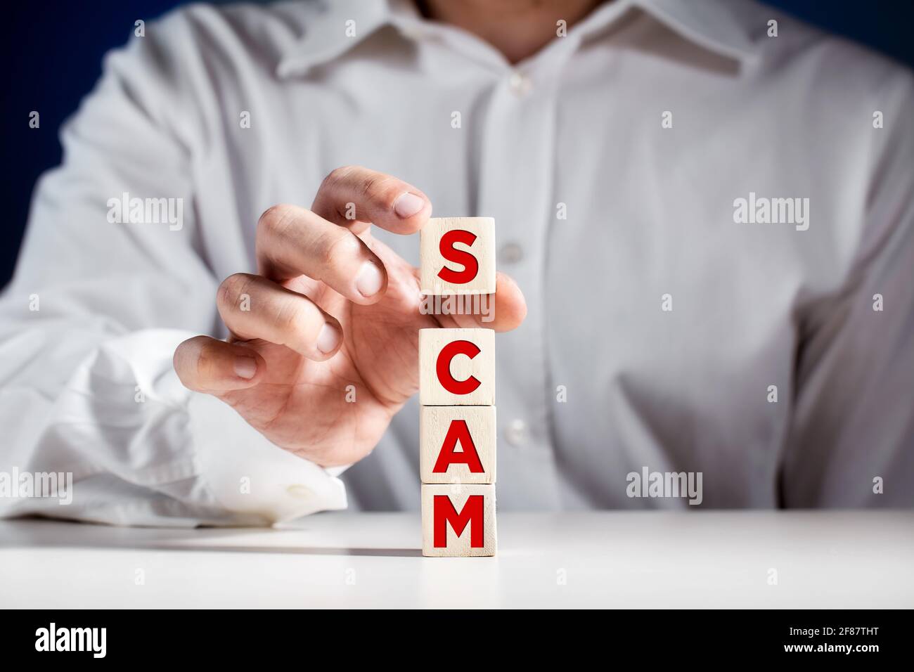 Uomo d'affari stira cubetti di legno con la parola TRUFFA. Frode criminalità nel mondo degli affari o concetto di criminalità informatica. Foto Stock