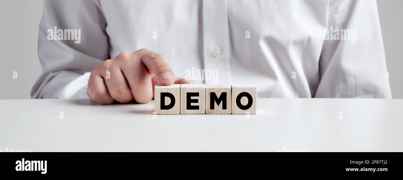 Uomo d'affari premendo il dito sui cubetti di legno con la parola demo. Test dimostrativo o concetto di prova. Foto Stock