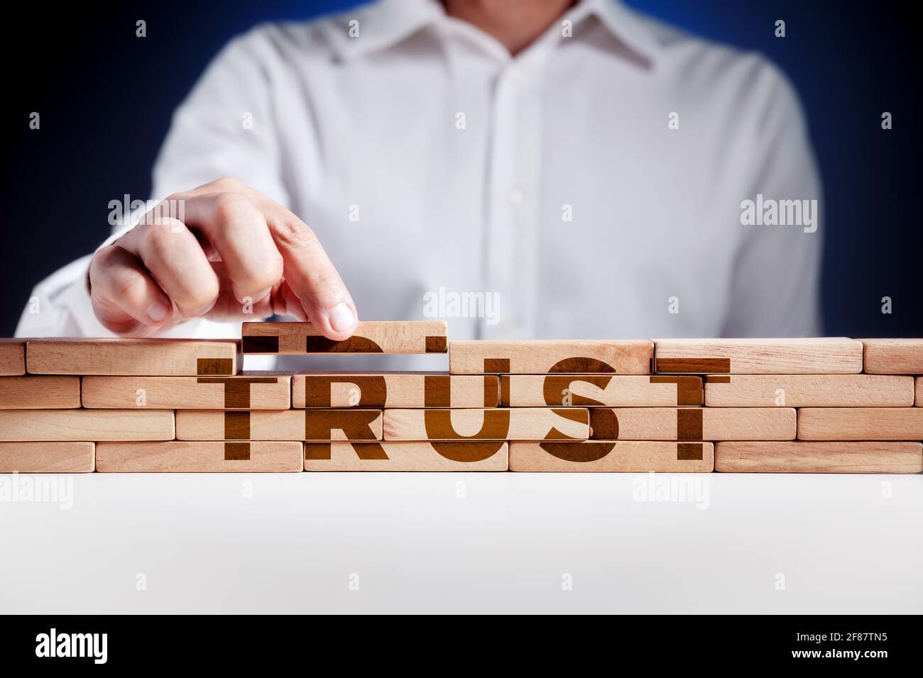 Uomo d'affari costruisce una struttura di blocchi di legno con la parola fiducia. Creare fiducia nel concetto aziendale. Foto Stock