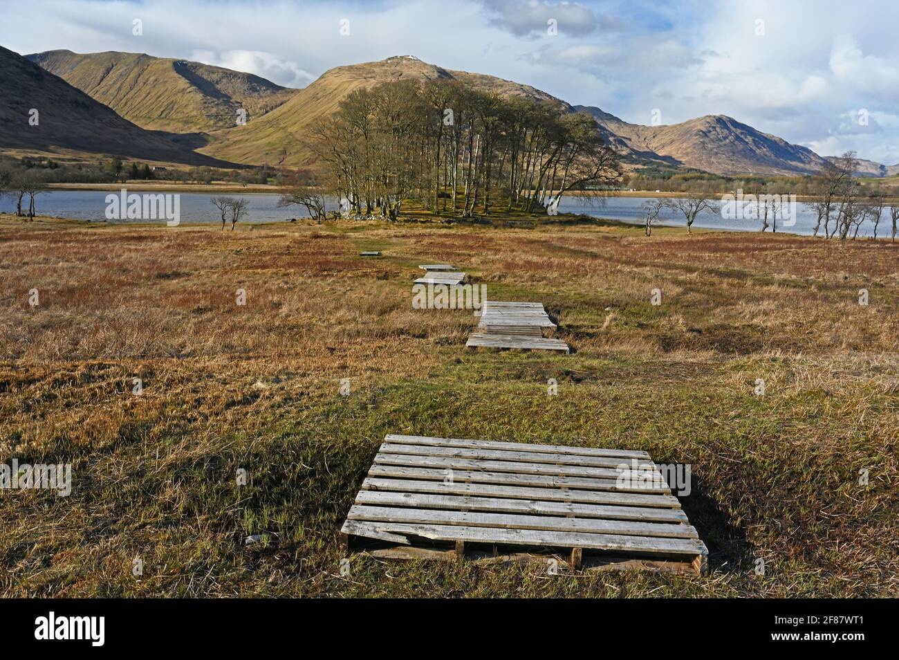 Vista verso Loch awe in Argyll e Bute, Highlands scozzesi con passerelle che formano la linea di guida verso piccoli boschi collinari, lago d'acqua e mountai Foto Stock