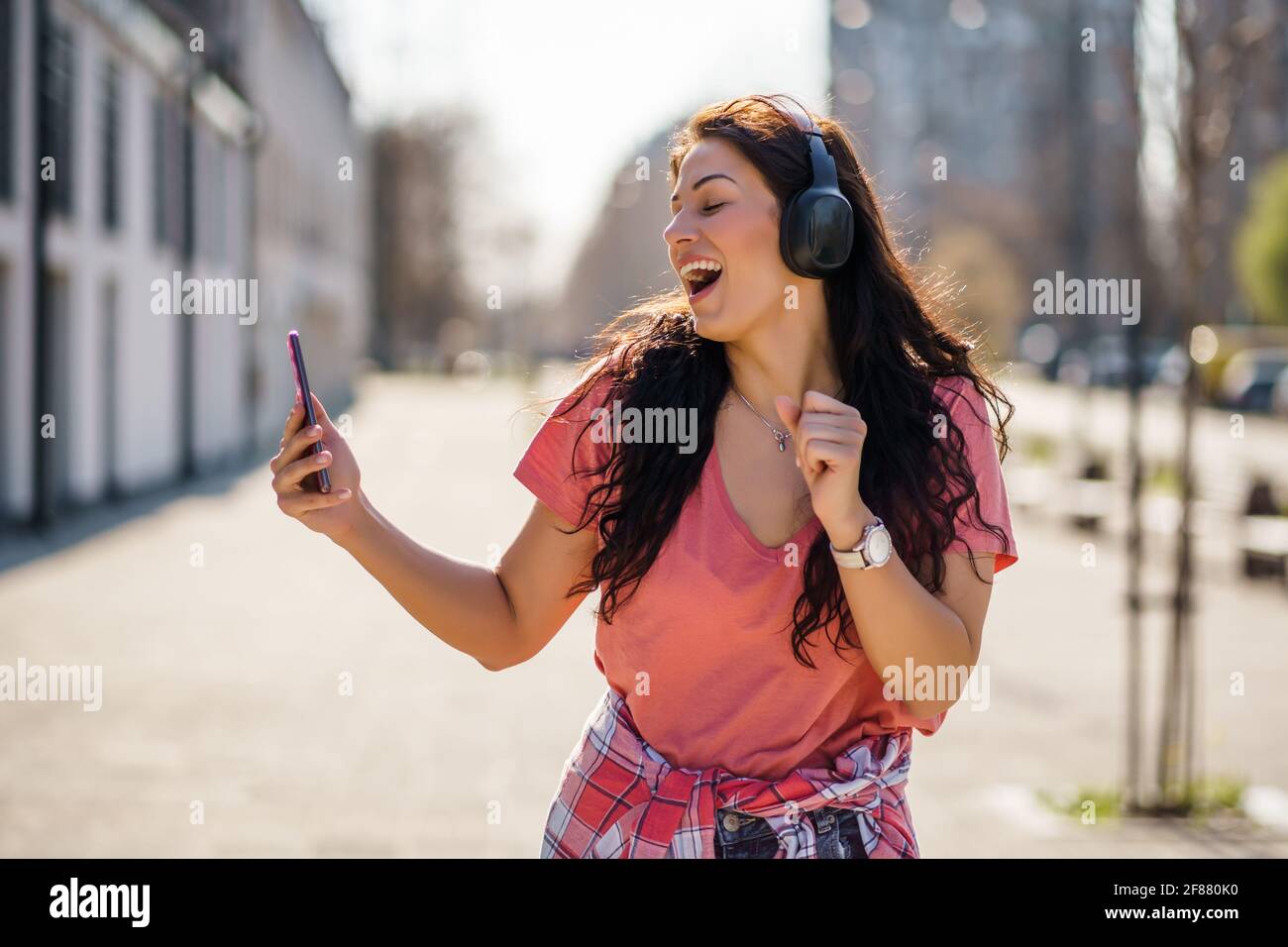 Felice giovane donna sta godendo di una giornata di sole all'aperto in città. Foto Stock
