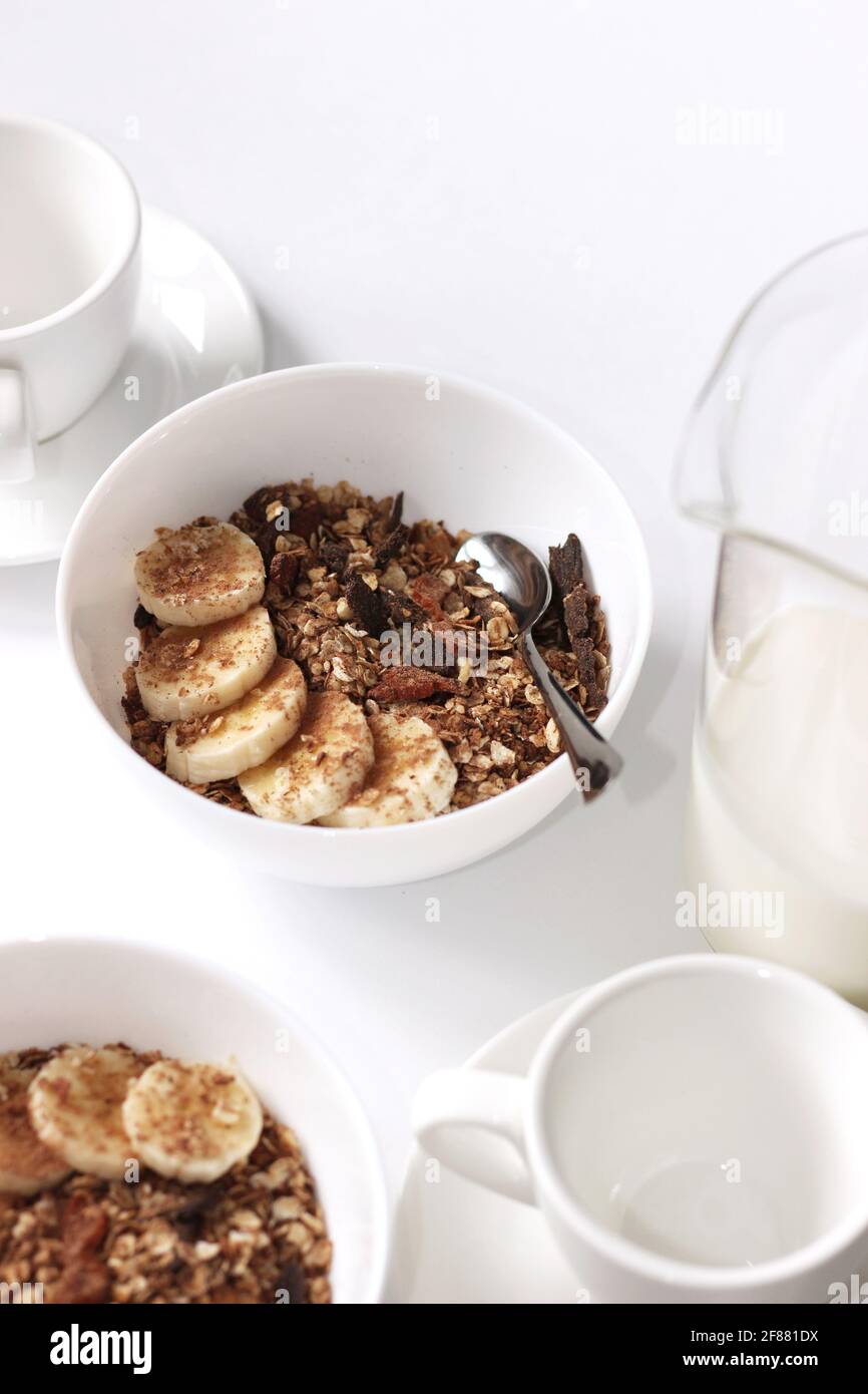 Home colazione servita su tavola bianca. Ciotole per cereali con vasetto di  latte e tazze da caffè Foto stock - Alamy