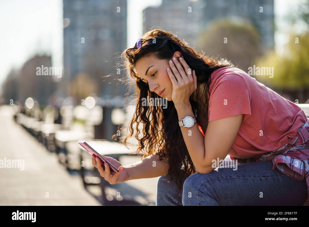 Triste giovane donna è seduta su panchina in città. È depressa. Foto Stock