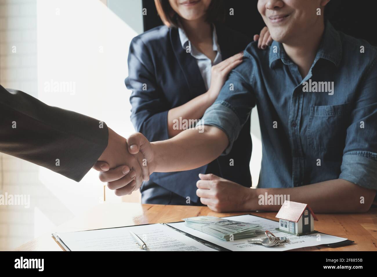 Giovane coppia asiatica scuotendo le mani con l'agente immobiliare dopo la firma del contratto. Concetto di bene immobile. Foto Stock