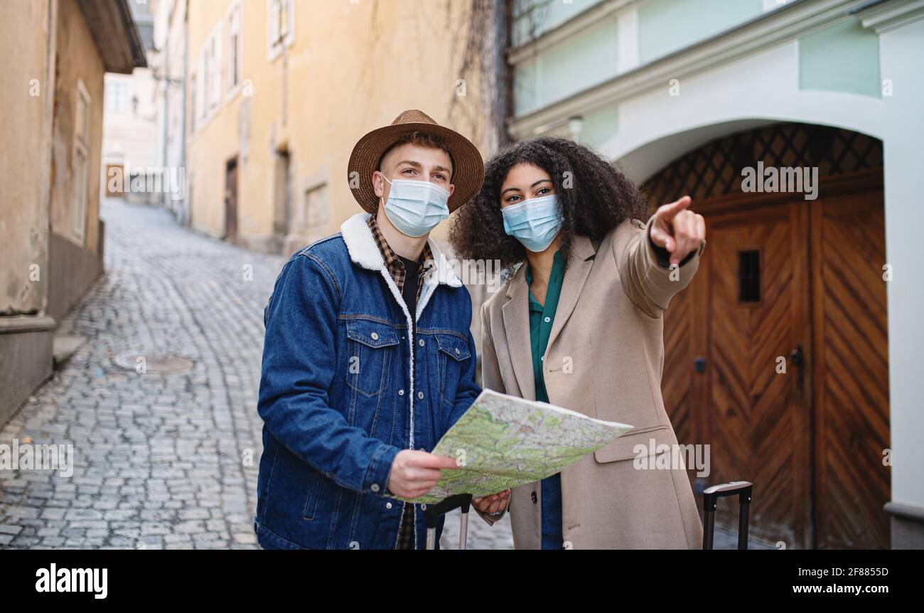 Giovani coppie di turisti con mappa sulla vacanza nel centro storico, concetto di coronavirus. Foto Stock