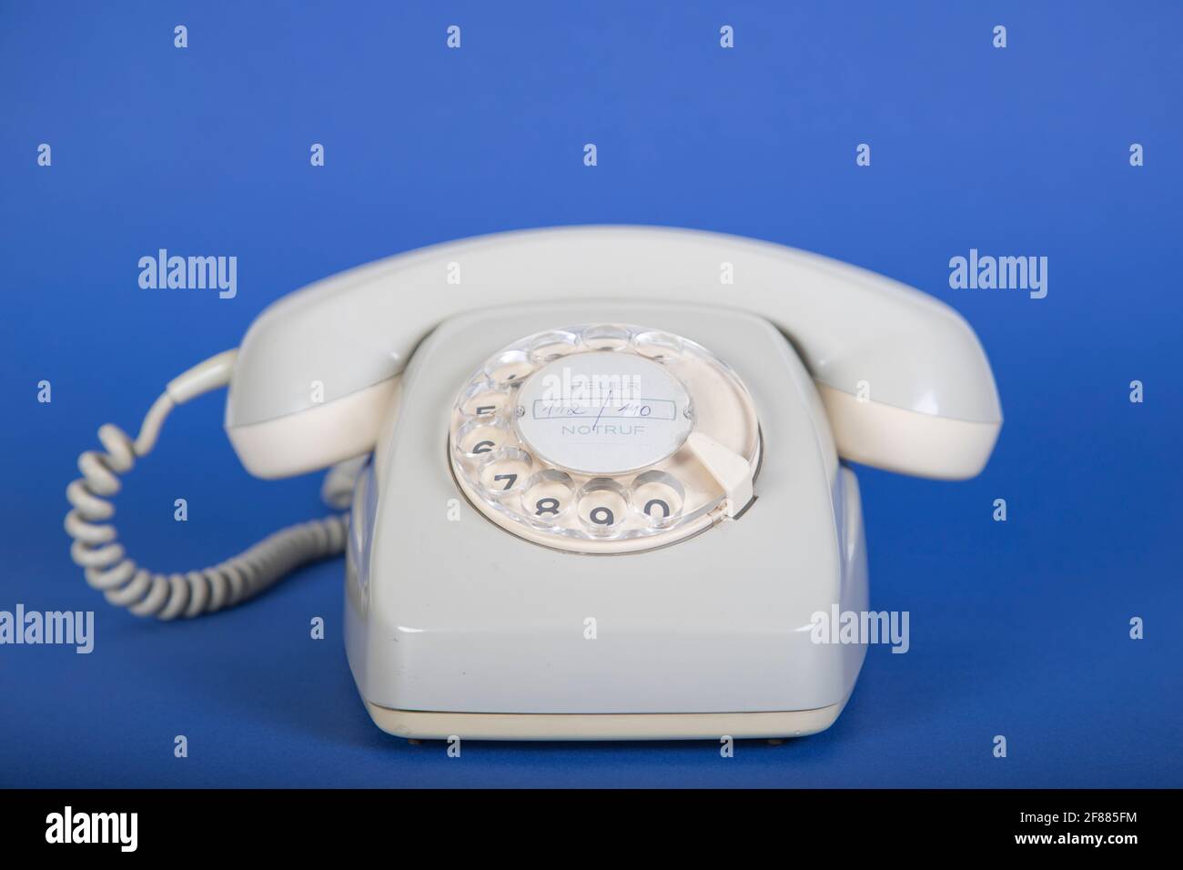 vecchio telefono grigio con platorello, sfondo blu Foto Stock