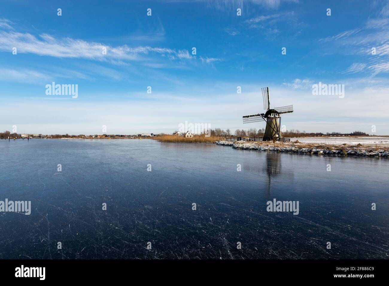 Paesaggio invernale con ghiaccio sul Dieperpoel (Kagerplassen) di fronte a un mulino a vento (de Kok) e casa sul Kogjespolder nei Paesi Bassi. Foto Stock