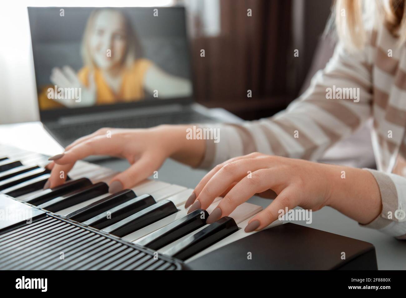 Donna che suona il pianoforte durante la videochiamata via computer  portatile. Il pianista musicista femminile migliora le capacità di suonare  le lezioni di pianoforte online con l'insegnante. Musi online Foto stock -