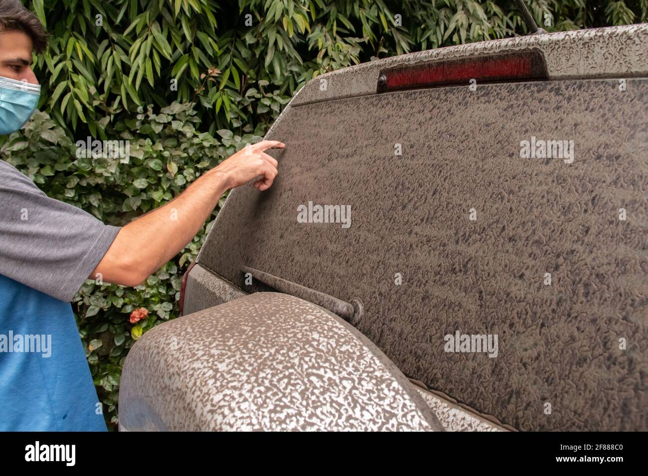 St. James, Barbados - Aprile 11 2021: Uomo con maschera scritta sul finestrino posteriore di un veicolo grigio SUV rivestito in cenere vulcanica da St. Vincent's la soufriere. Foto Stock