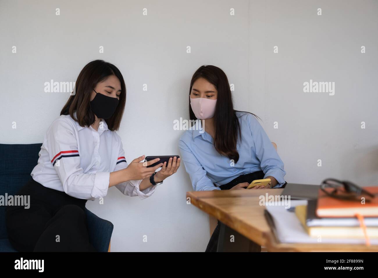 Giovane studente che guarda le ultime notizie elettroniche sullo smartphone in classe. Foto Stock