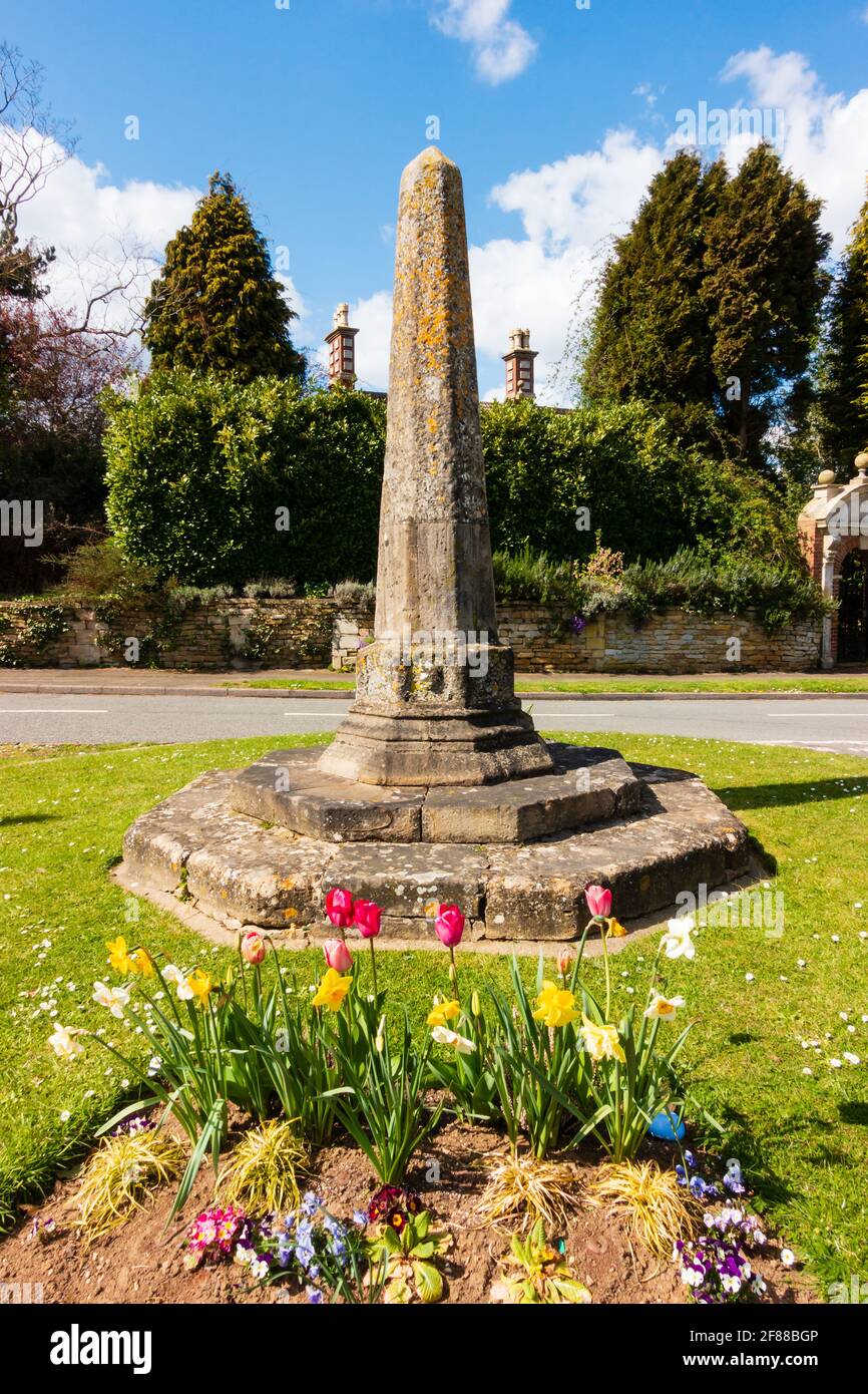 Il vecchio Obelisco Market Cross con tulipani e fiori. Harlaxton, vicino Grantham, Lincolnshire, Inghilterra. Foto Stock