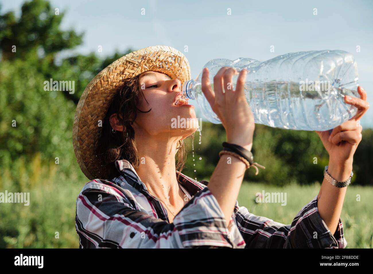 Donna contadina con boccaglio di acqua in un campo di coltura Foto Stock