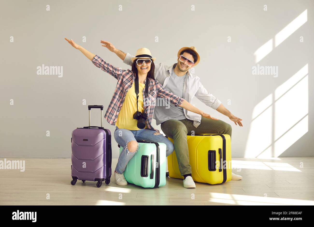 Felici coppie di turisti che tengono le mani come le ali che volano seduto borsa per valigie Foto Stock