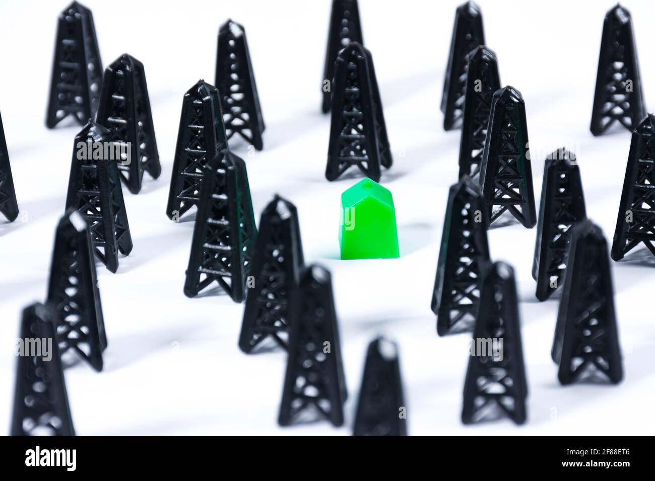 Una casa giocattolo verde tra le piattaforme petrolifere. Concetti come il pericolo di contaminazione, ecologia, molestie di proprietà o classe sociale Foto Stock
