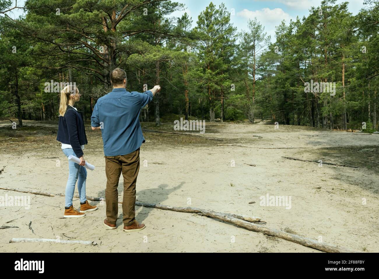 uomo e donna cercano un appezzamento di terra per costruzione di casa di campagna. copia spazio Foto Stock