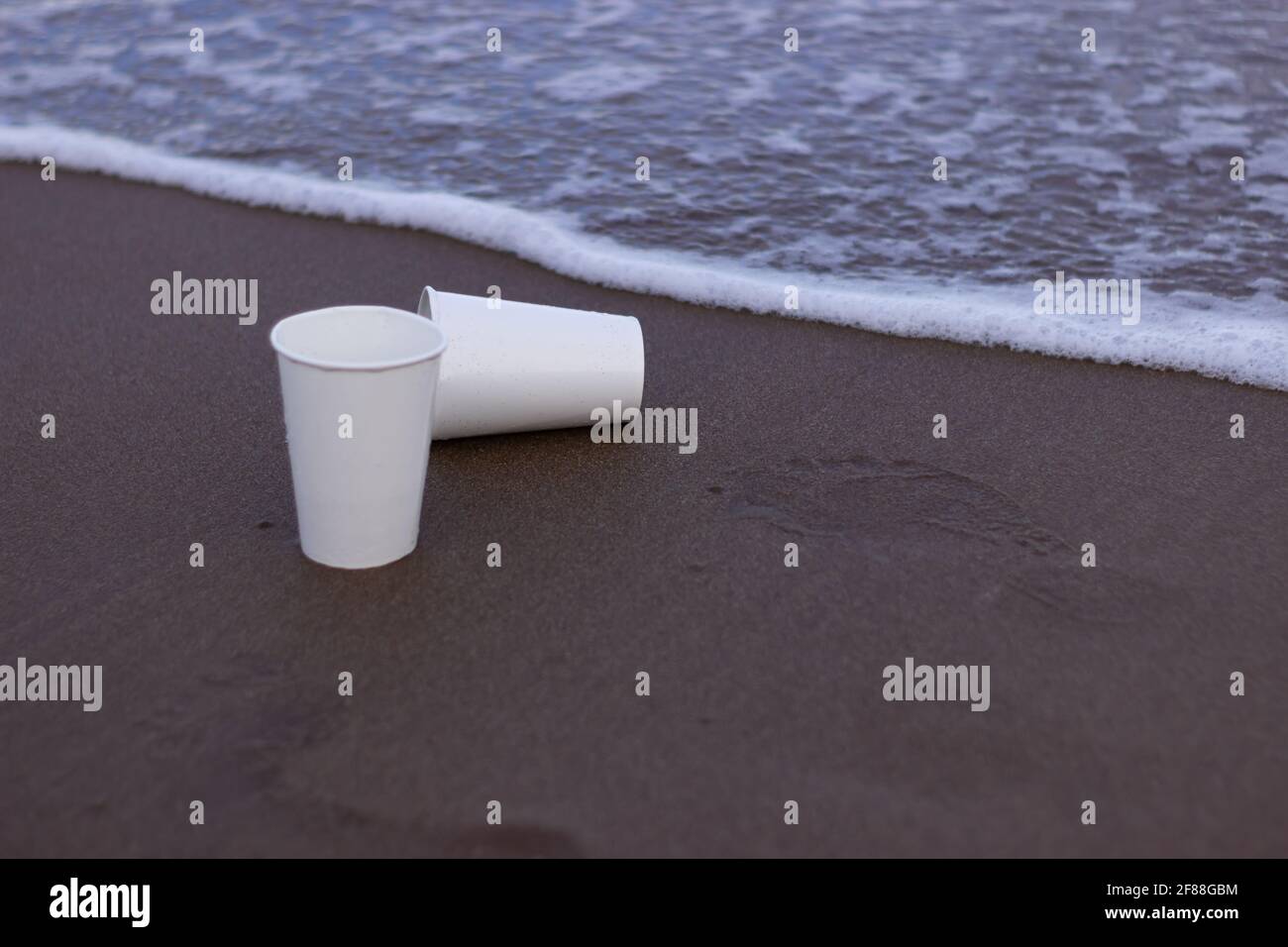 Due tazze di plastica sulla sabbia. Foto Stock