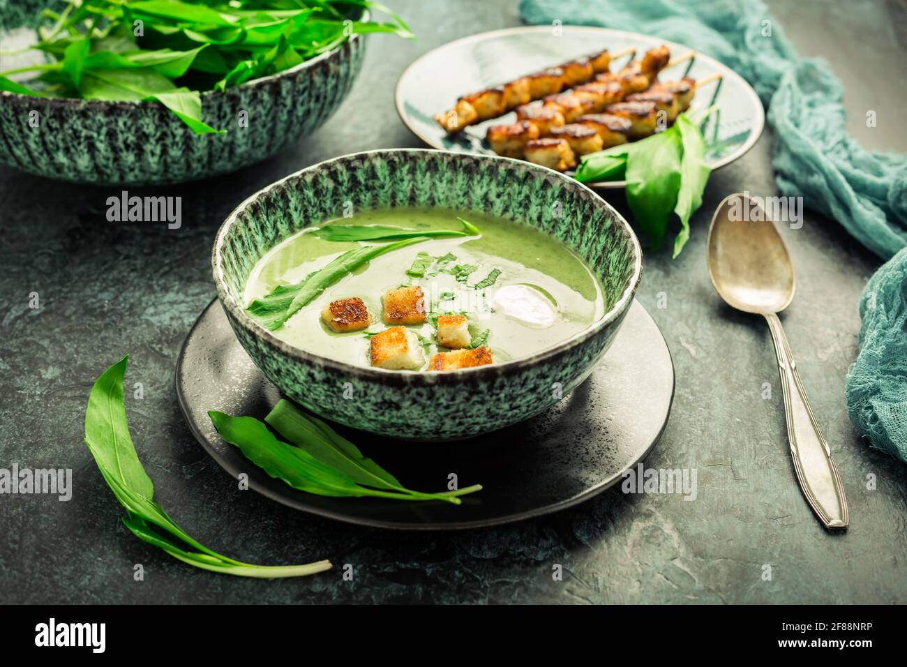 Zuppa di porri o zuppa di ramson con crostini, panna acida e spiedino di tacchino su sfondo verde Foto Stock