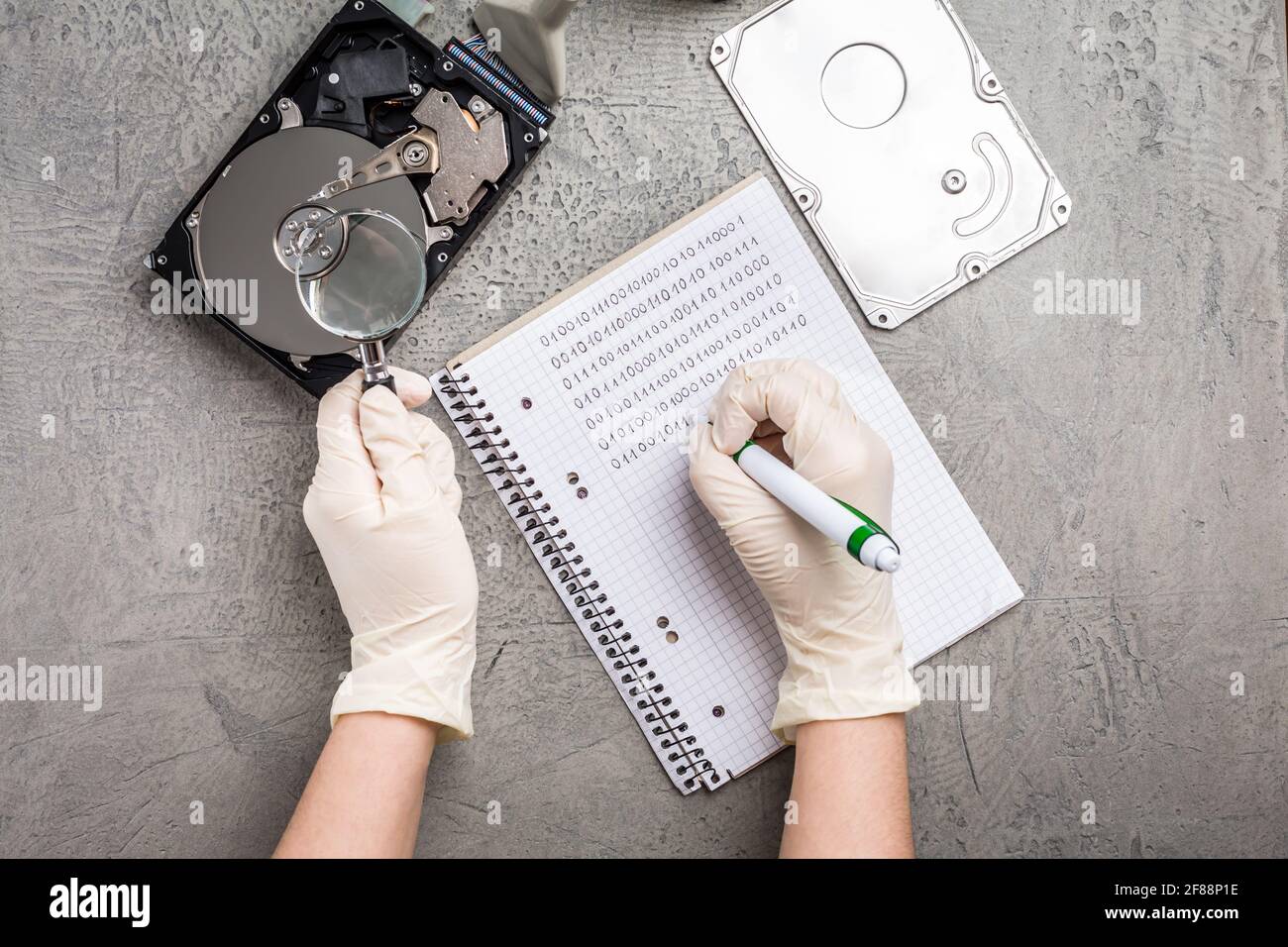 Concetto di recupero dei dati, il tecnico sta recuperando i dati dal driver del disco rigido guasto. Ripristino disco HDD, lente di ingrandimento e codice binario Foto Stock