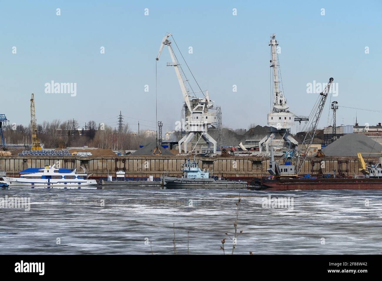 Porto sul fiume. La fabbrica vicino al fiume. Estrazione di sabbia. Una gru e attrezzatura speciale per il carico della sabbia. Foto Stock