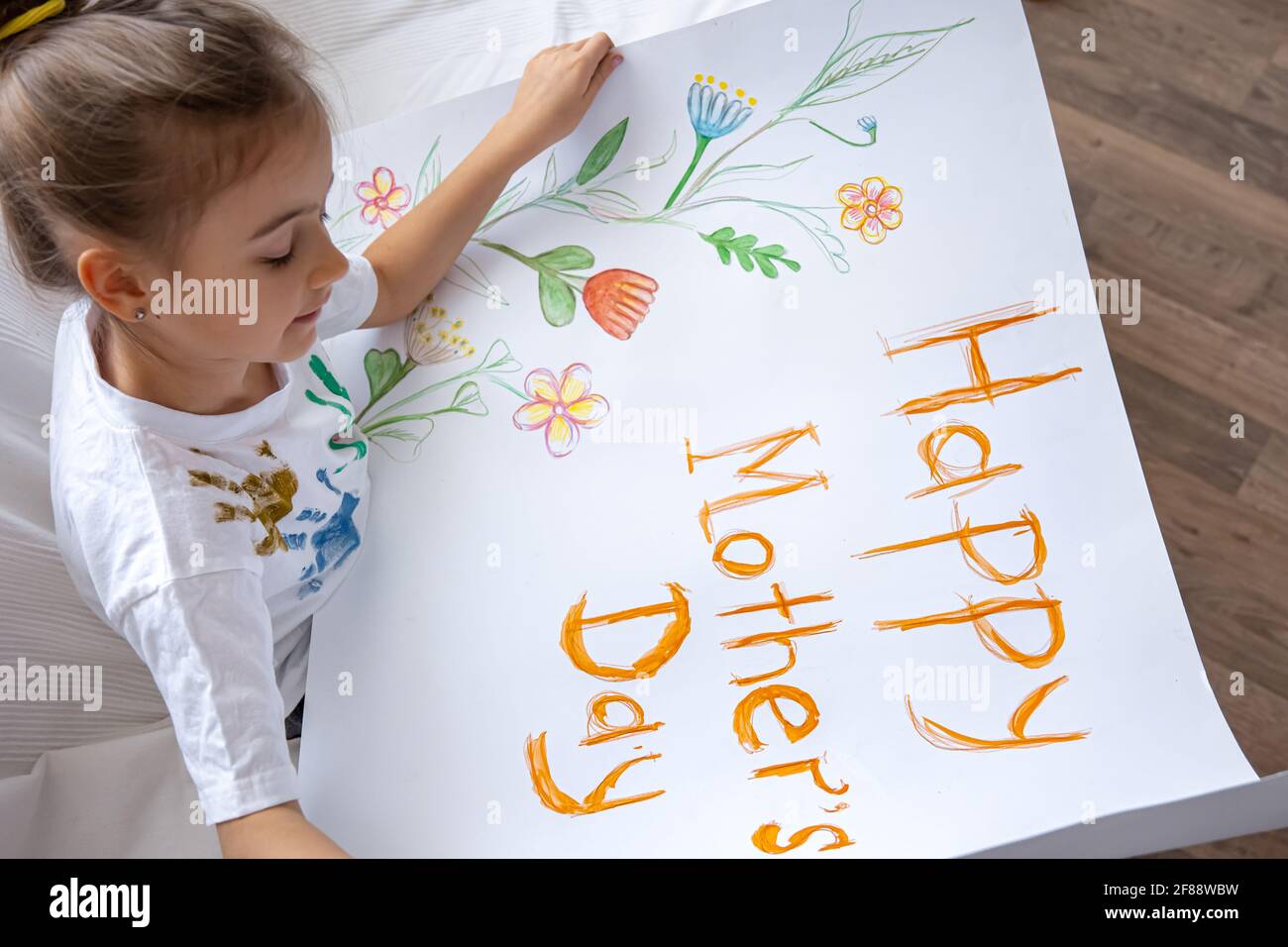 La bambina dipinge il biglietto d'auguri per la mamma il giorno della mamma con l'iscrizione Happy Mother's Day. Foto Stock