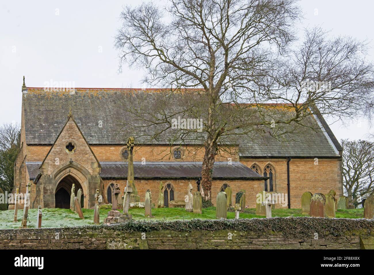 St Helen's e All Saints, antico villaggio di campagna inglese con cimitero e muro di pietra a secco nella comunità rurale Foto Stock