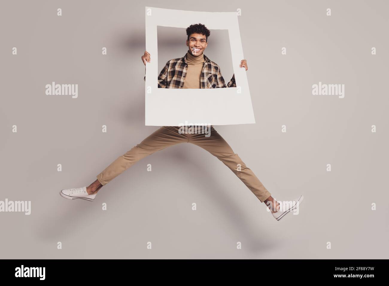 Foto a grandezza naturale di pelle scura bello uomo salto usura i vestiti casual tengono la cornice isolata su sfondo di colore grigio Foto Stock