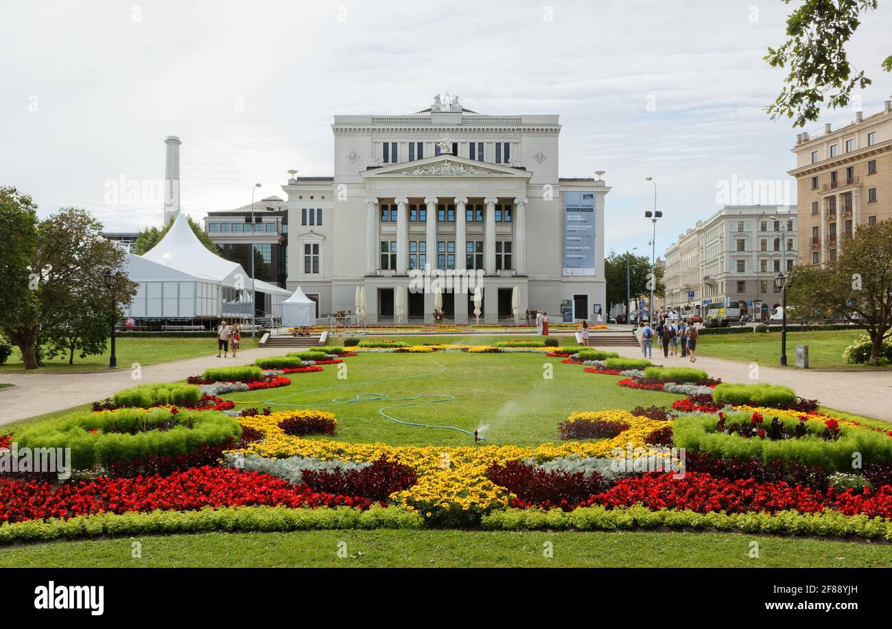 RIGA, Lettonia - 27 luglio 2013: Teatro Nazionale dell'Opera lettone e il bellissimo letto fiorito di fronte Foto Stock