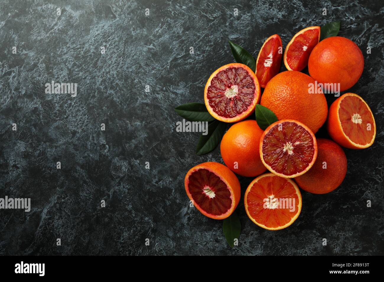 Arance rosse e foglie su sfondo nero fumoso Foto Stock