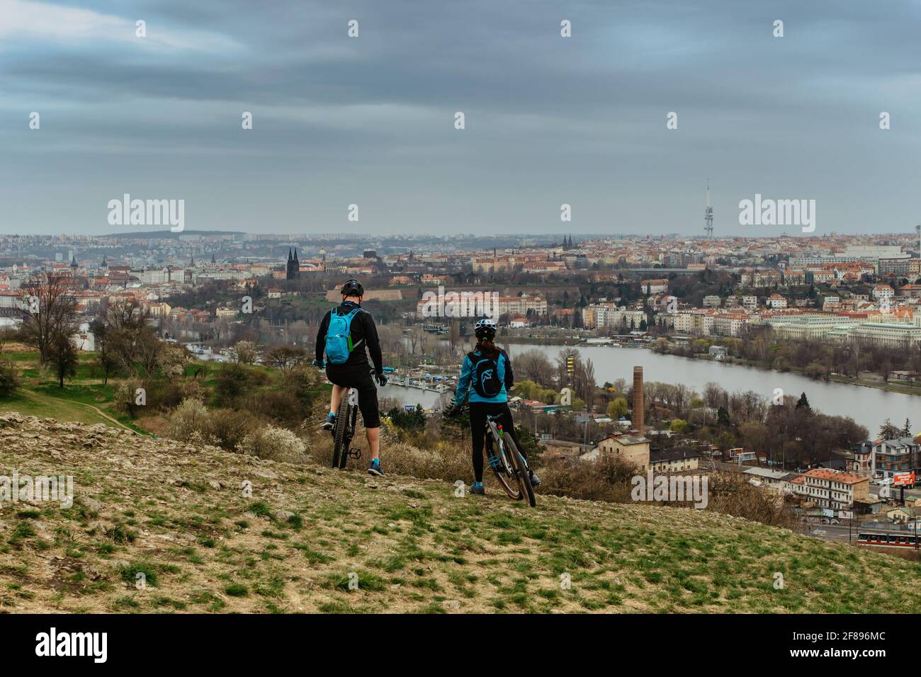 Due ciclisti che godono di vista dello skyline della città di Praga e del fiume Moldava, Repubblica Ceca. Paesaggio attraente con valle profonda, sentieri escursionistici, panorama di Praga Foto Stock
