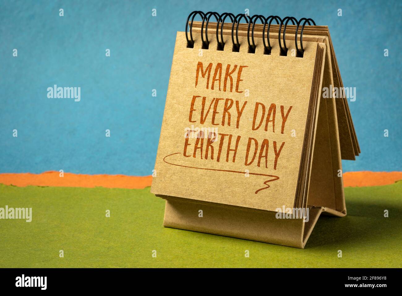 rendi ogni giorno la nota ispiratrice del giorno della terra - la scrittura a mano in un piccolo calendario desktop contro il paesaggio astratto della carta, il concetto ambientale Foto Stock