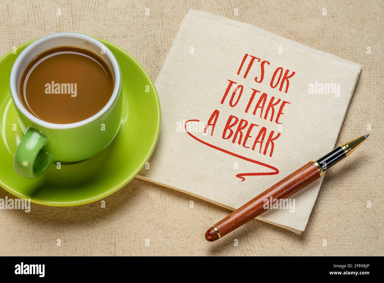 E 'OK per fare una pausa - inspirazione scrittura a mano su un tovagliolo con una tazza di caffè, cura di sé, stress, overworking concetto Foto Stock