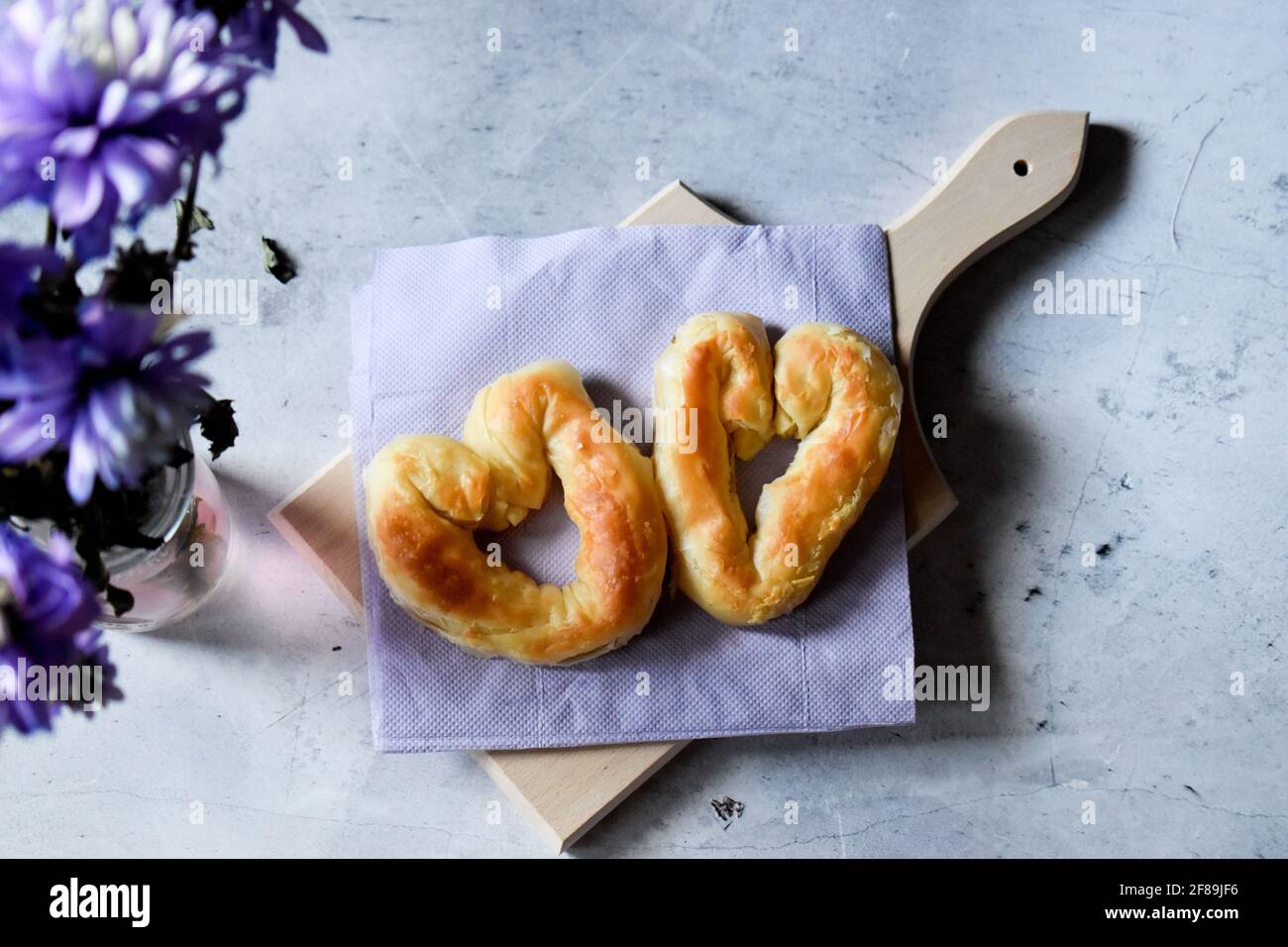 Pasticceria con formaggio e fiori viola su un tavolo grigio Foto Stock