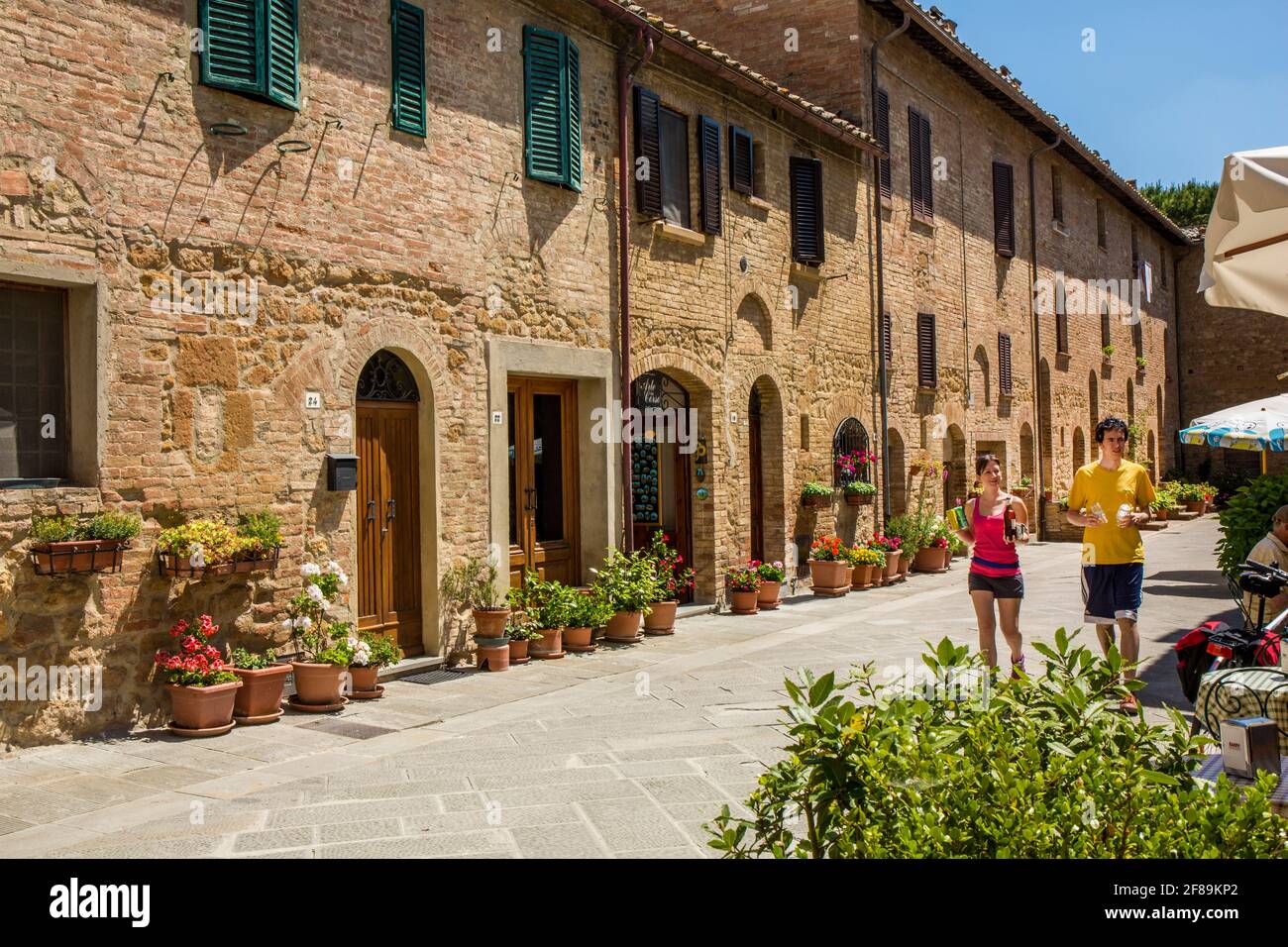 Pienza, Toscana, Italia. Turisti con bevande godendo di una passeggiata in questa città patrimonio dell'umanità dell'UNESCO. (Solo per uso editoriale) Foto Stock