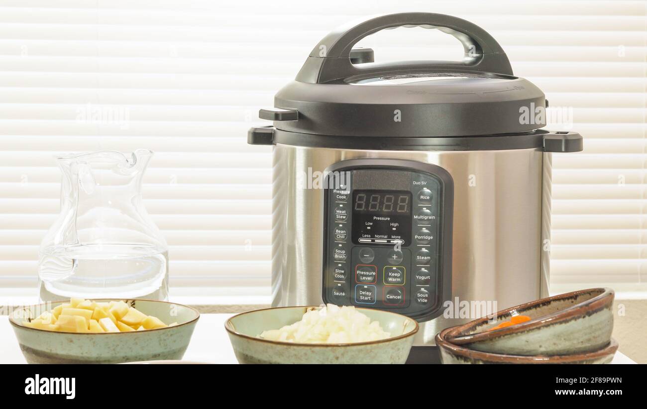 Moderno fornello elettrico multiplo con alcuni ingredienti per le esigenze di cottura primo piano sul tavolo da cucina Foto Stock