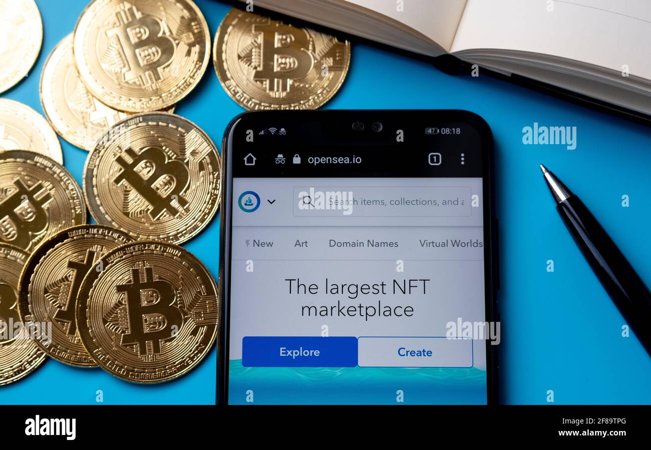 Mercato di Opensea di NFT per il commercio del Web site di arte digitale del token non fungibile visto sullo smartphone messo vicino a Bitcoins. Stafford, Regno Unito, aprile Foto Stock