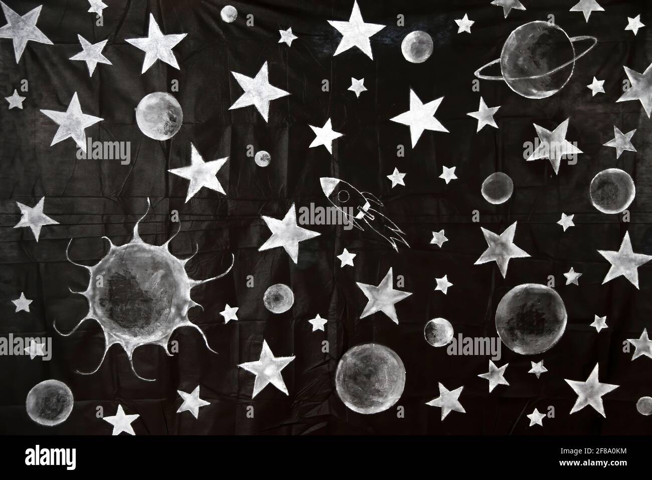 uno sfondo in tessuto nero decorato con disegni per bambini di stelle, pianeti e un divertente razzo spaziale, sfondo con temi spazio e sistema solare, Foto Stock