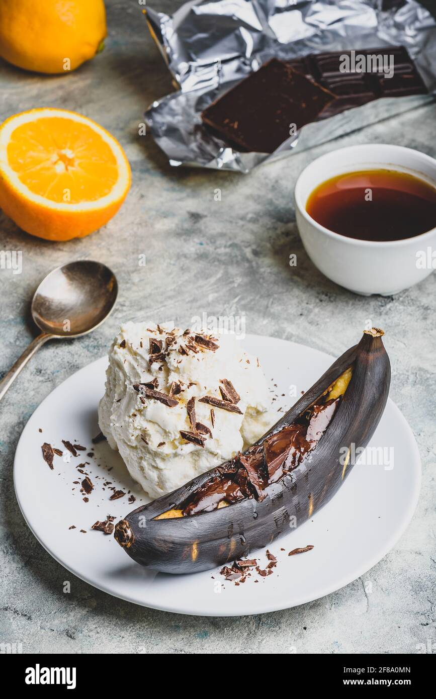 Dolce dessert. Banana alla griglia con cioccolato fondente, succo di agrumi e gelato alla vaniglia. Foto Stock