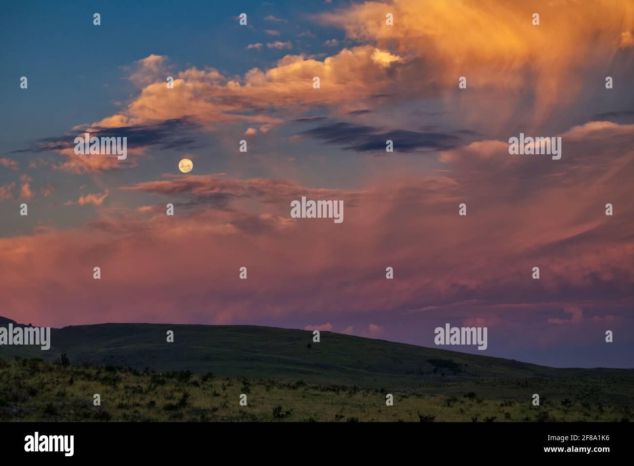 Luna piena in un cielo di tramonto drammatico Foto Stock